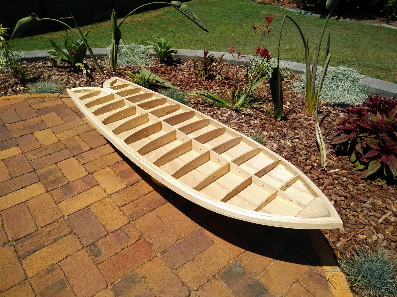 Skin-on-frame hollow wooden surfboard skeleton with plywood spine, ribs and a timber perimeter rail