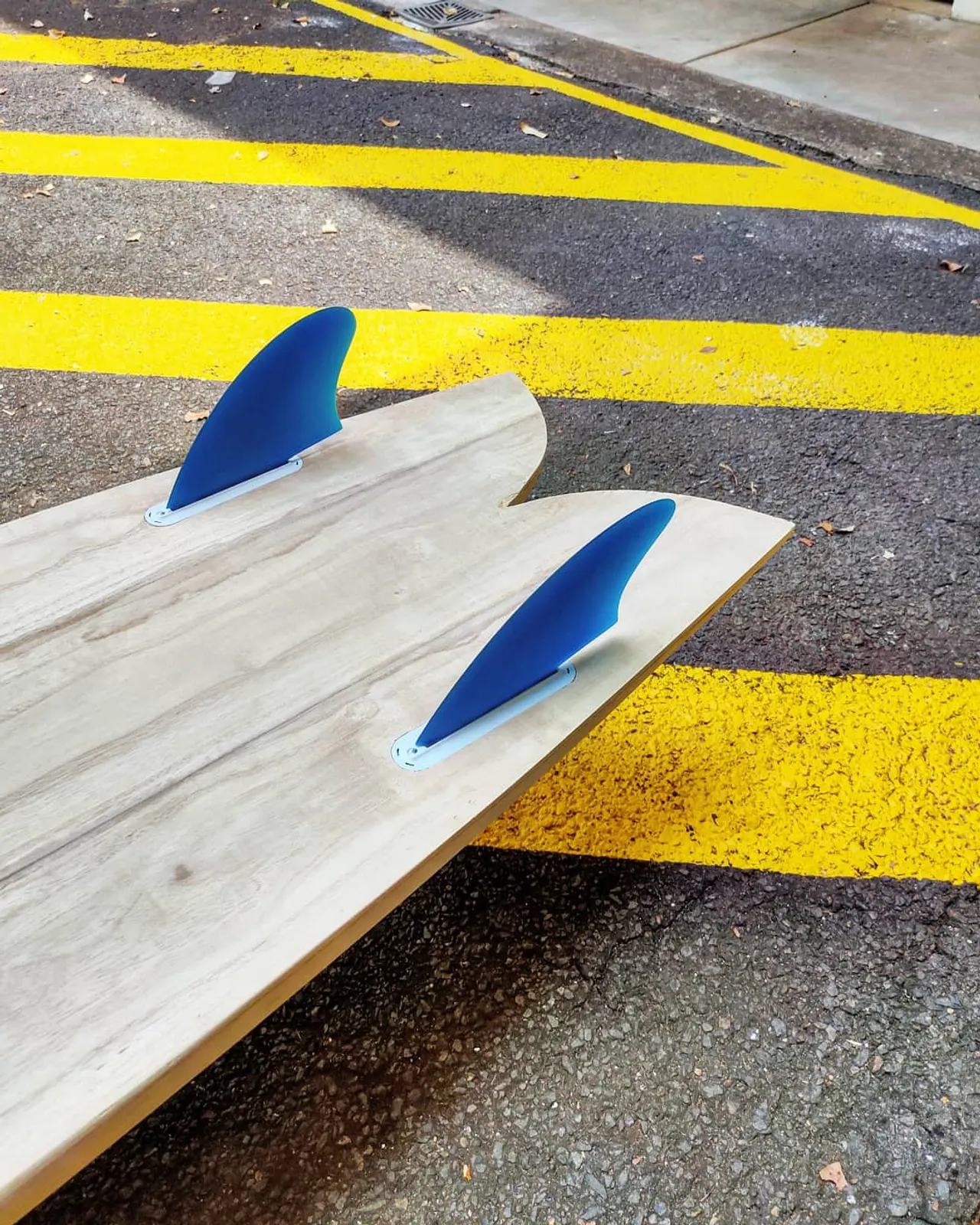 Twin keel fins fitted beside the swallow tail of a hollow wooden fish surfboard